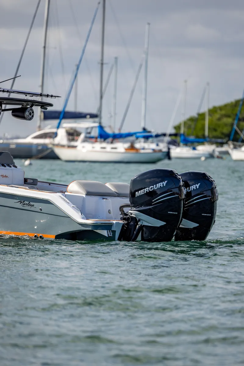 Slide: The Image of 2005 Marlago 35 boat with twin Mercury engines on water, sailboats in background. - 4