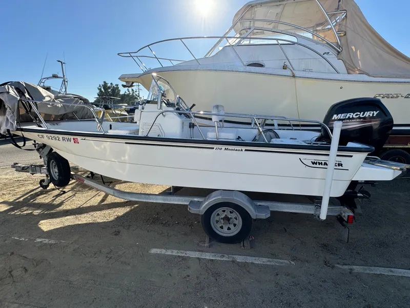The Image of 2016 Boston Whaler 170 Montuck boat on trailer, parked outdoors, with Mercury engine. - 1