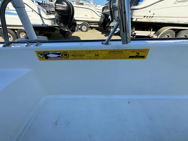 Slide: The Image of 2016 Boston Whaler 170 MONTUCK boat interior with safety label, docked near other boats. - 19