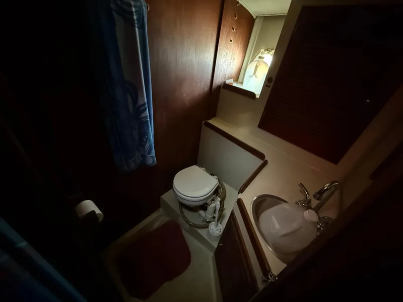 Slide: The Image of Compact bathroom in a 1973 Islander 40 sailboat, featuring a toilet, sink, and wooden cabinetry. - 11