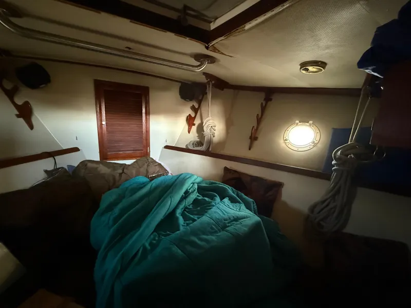 Slide: The Image of Cozy cabin interior of a 1973 Islander 40 sailboat with porthole and teal bedding. - 12