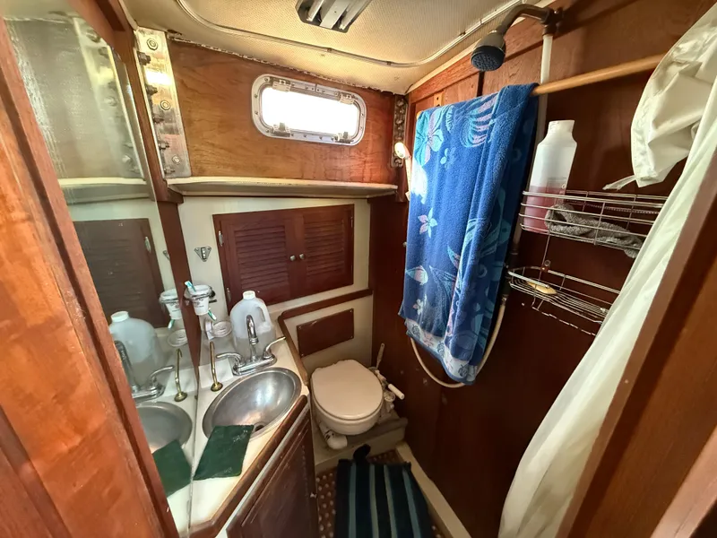 Slide: The Image of 1973 Islander 40 yacht bathroom with wooden cabinetry, dual sinks, and nautical decor. - 16