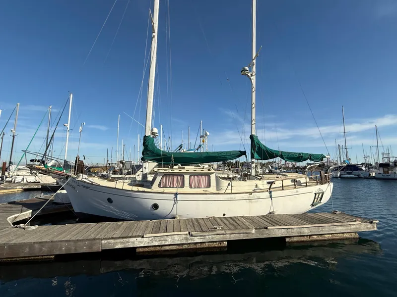 Slide: The Image of 1973 Islander 40 sailboat docked at marina under clear blue sky. - 3