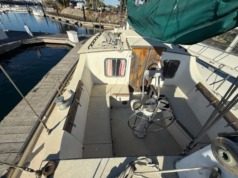 Slide: The Image of 1973 Islander 40 sailboat cockpit with steering wheel, docked at marina. - 5