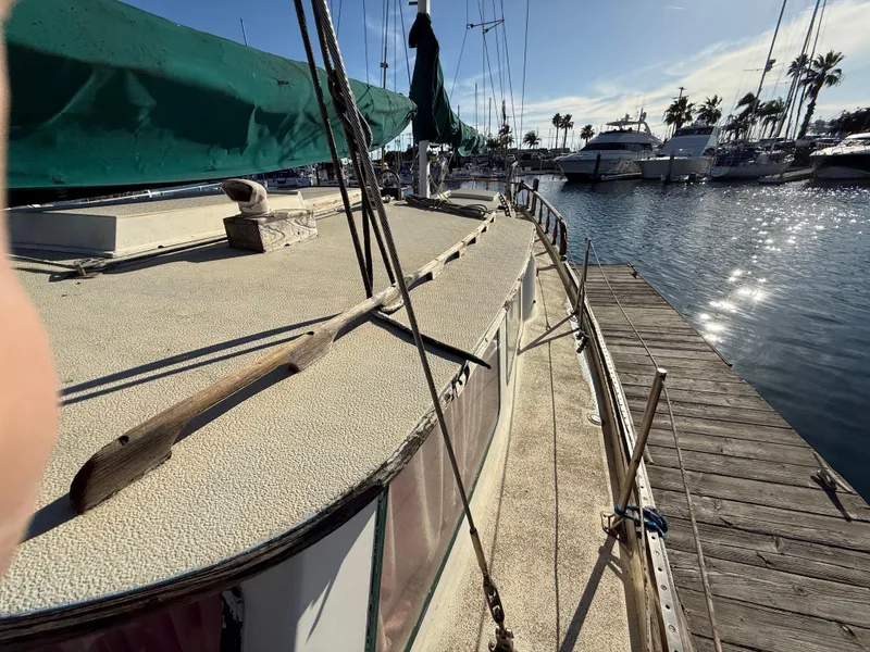 Slide: The Image of 1973 Islander 40 sailboat docked at a marina, sunny day, calm water, palm trees in background. - 6