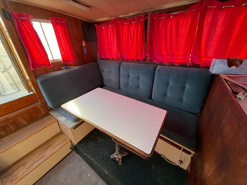Slide: The Image of Interior of 1973 Islander 40 boat with red curtains and a cozy dining area. - 9