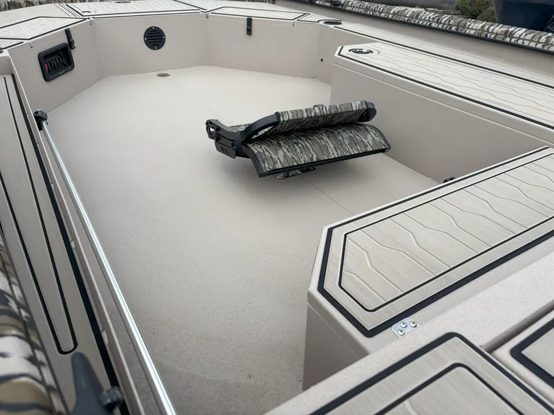 Slide: The Image of 2025 Avid 18 Commander boat interior with camo seating and storage compartments. - 18