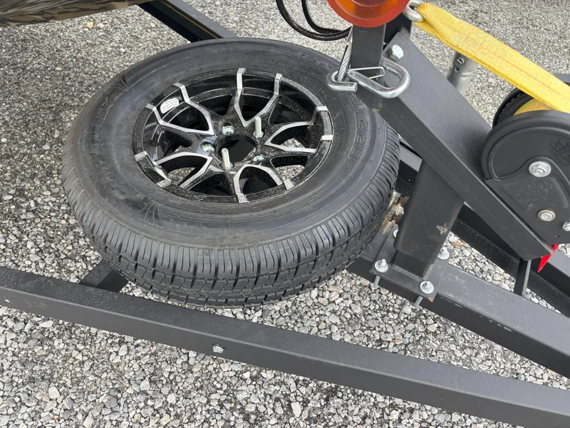 Slide: The Image of 2025 Avid 18 Commander trailer with spare tire on gravel surface. - 20