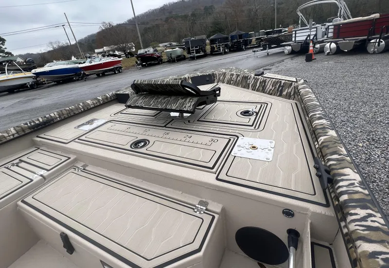 Slide: The Image of 2025 Avid 18 Commander boat with camouflage interior, parked in a lot with other boats. - 4