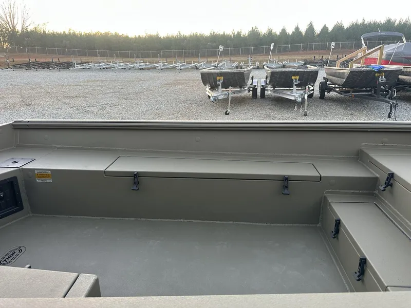 Slide: The Image of 2025 Thor Lake Hammer 1754 boat interior with storage compartments, parked on gravel lot. - 4