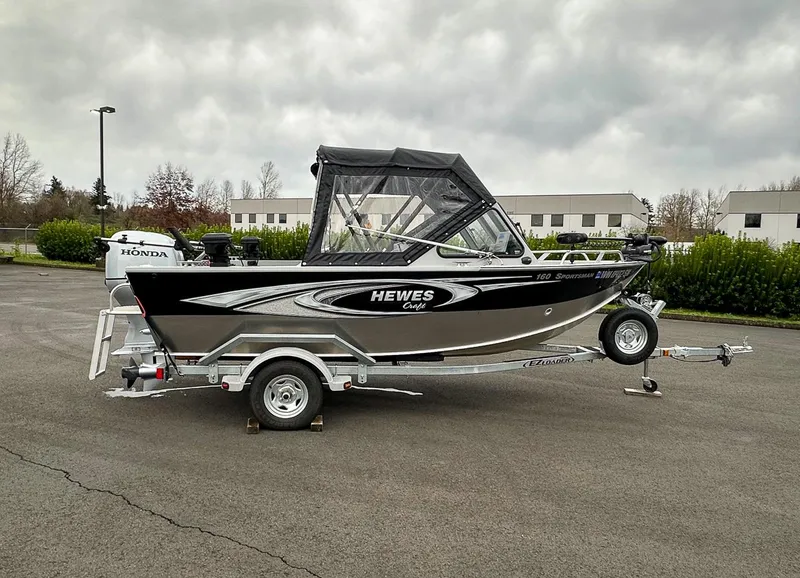 Slide: The Image of 2017 Hewescraft 160 Sportsman boat on trailer, parked outdoors under cloudy sky. - 1