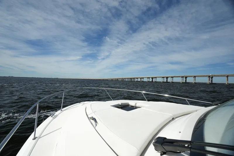 Slide: The Image of 2023 Pursuit OS 355 Offshore boat cruising under a blue sky near a bridge. - 17