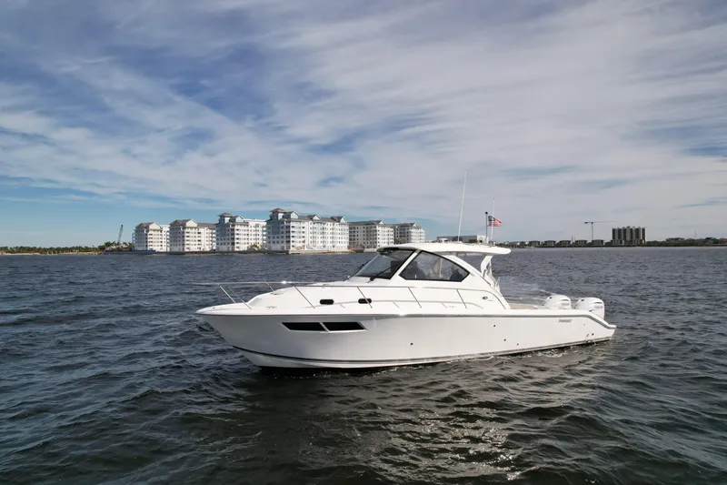 Slide: The Image of 2023 Pursuit OS 355 Offshore boat on open water with buildings in the background. - 2