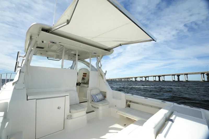Slide: The Image of 2023 Pursuit OS 355 Offshore boat with canopy, on water near a bridge. - 22