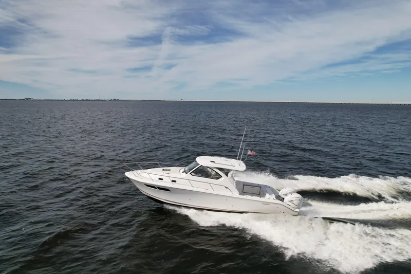 Slide: The Image of 2023 Pursuit OS 355 Offshore cruising on open water under a clear sky. - 7