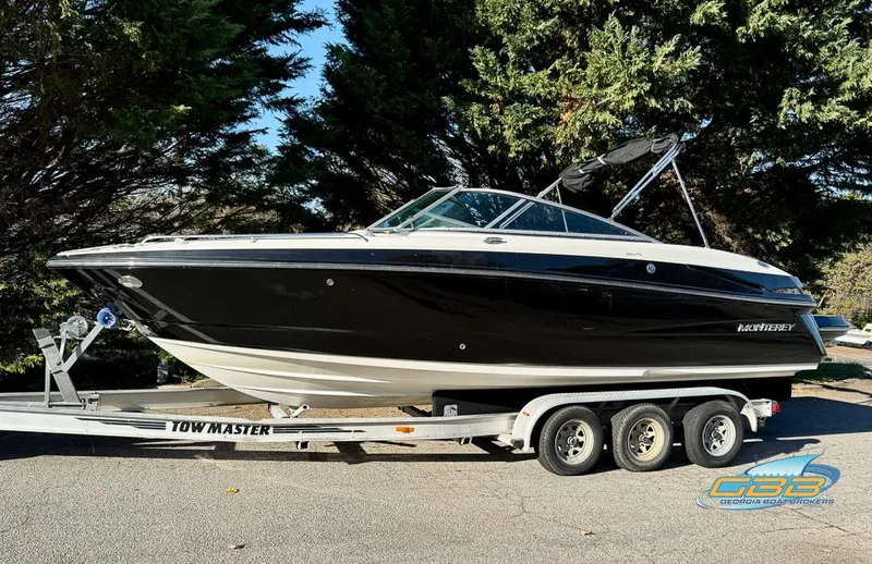 Slide: The Image of 2013 Monterey 264FS boat on trailer, parked outdoors, surrounded by trees. - 3