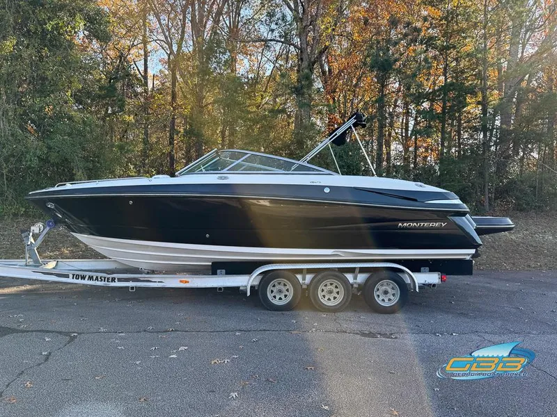 Slide: The Image of 2013 Monterey 264FS boat on trailer, parked outdoors, surrounded by trees. - 8