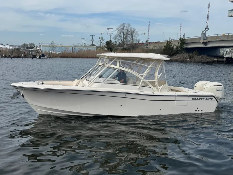 Slide: The Image of 2025 Grady-White Freedom 285 boat cruising on a calm river near a bridge. - 0