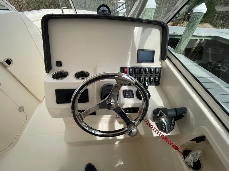 Slide: The Image of 2025 Grady-White Freedom 285 boat helm with steering wheel and control panel. - 16