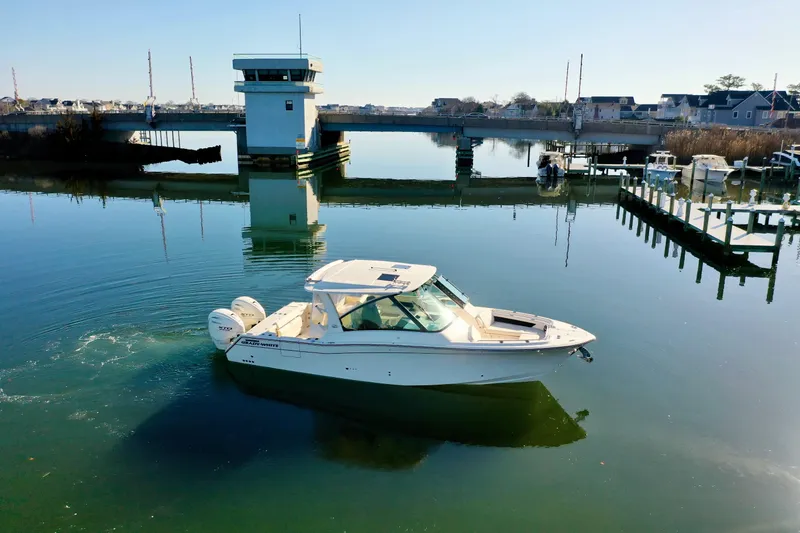 Slide: The Image of 2025 Grady-White Freedom 345 boat on calm water near a marina and bridge. - 12