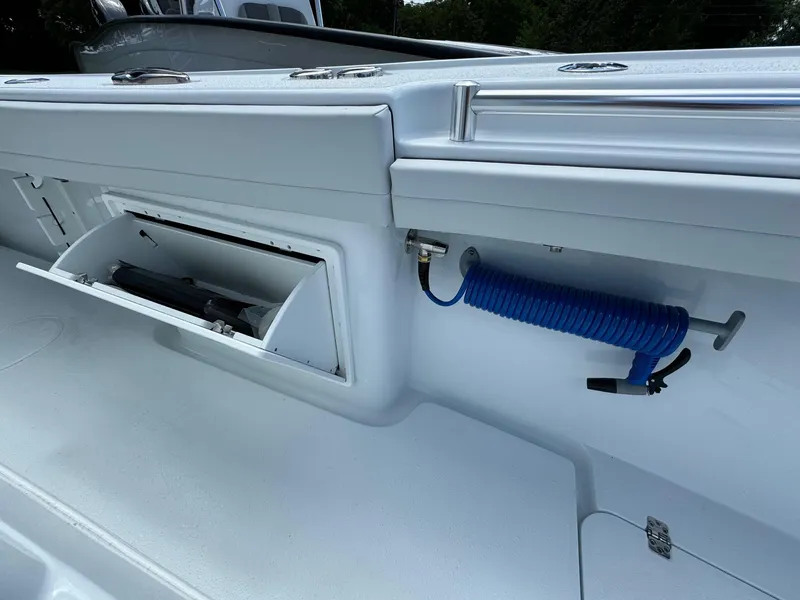 Slide: The Image of 2025 Yellowfin 32 Offshore boat interior with storage compartment and coiled hose. - 22
