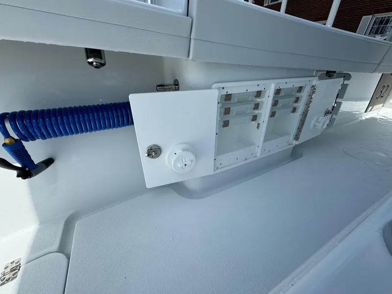 Slide: The Image of 2025 Yellowfin 32 Offshore boat interior with storage compartments and coiled blue hose. - 23