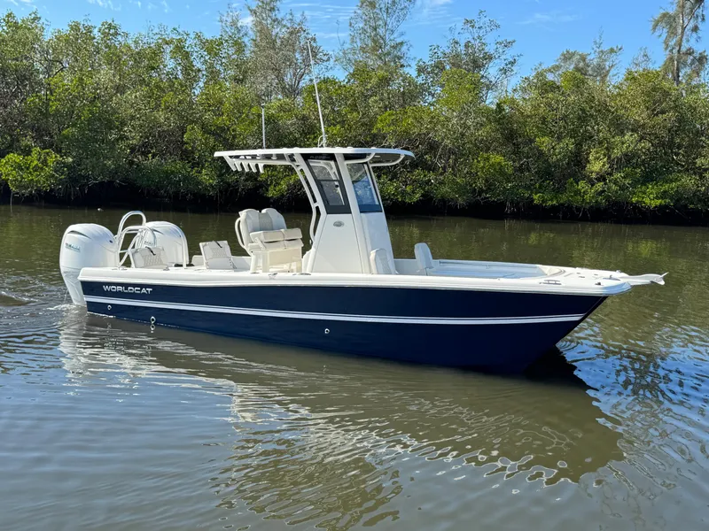 The Image of 2025 World Cat 235 CC boat on calm water, surrounded by lush greenery. - 1