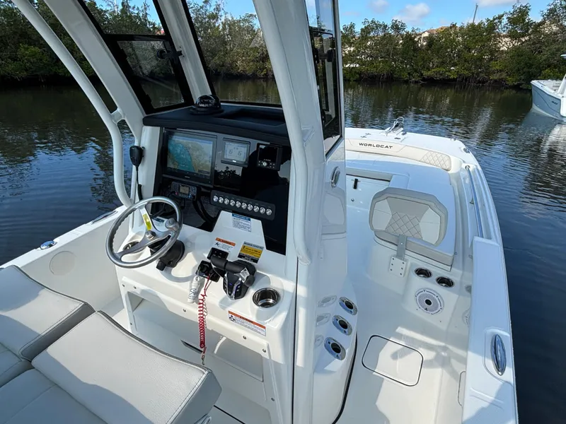 Slide: The Image of 2025 World Cat 235 CC boat interior with modern controls and seating, docked on calm water. - 12