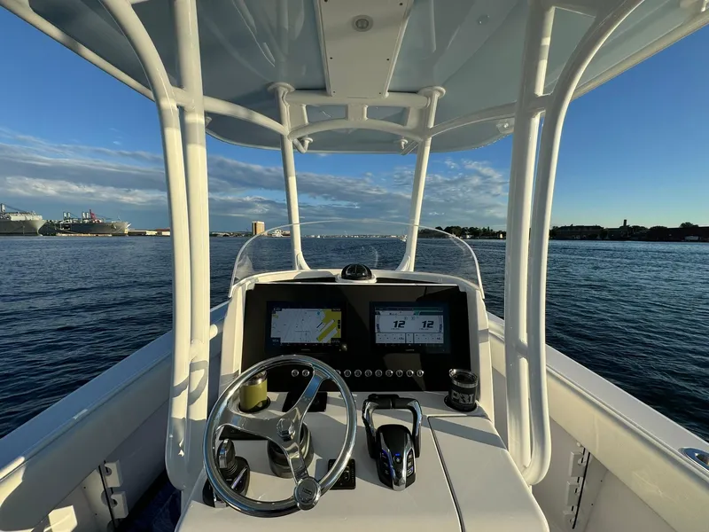 Slide: The Image of 2024 Jupiter 26 FS boat dashboard with steering wheel, navigational screens, and ocean view. - 23