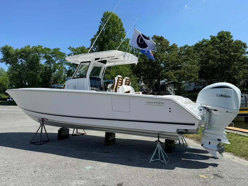 Slide: The Image of 2024 Jupiter 340LS boat on stands, outdoors, with Yamaha engine and flag. - 0