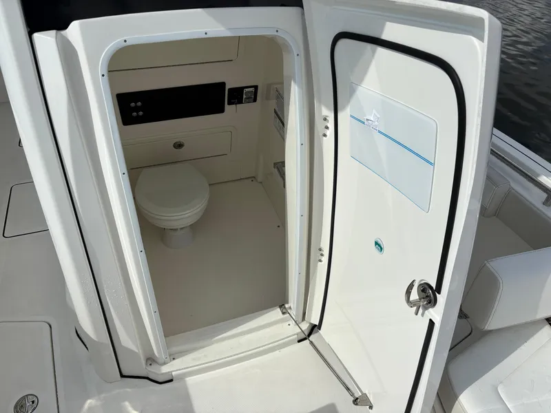 Slide: The Image of 2025 World Cat 260 CC-X boat interior with open door revealing compact marine toilet. - 18