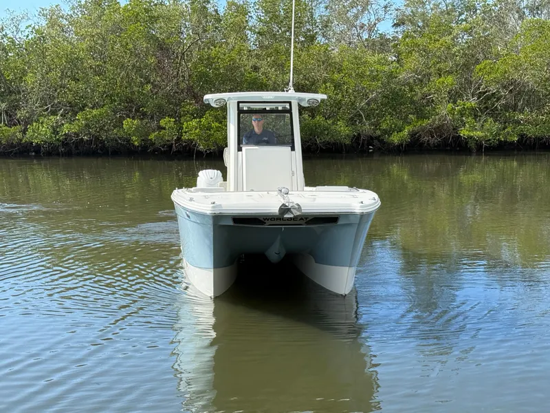 Slide: The Image of 2025 World Cat 260 CC-X boat navigating calm waters near lush greenery. - 2