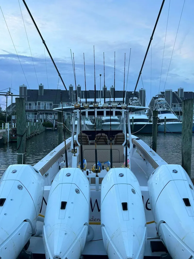 Slide: The Image of 2024 Jupiter 43 boat docked with multiple outboard engines, fishing rods visible. - 10