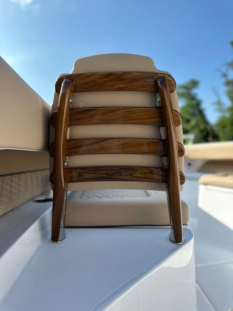 Slide: The Image of 2024 Jupiter 43 boat seat with wooden accents under clear blue sky. - 24