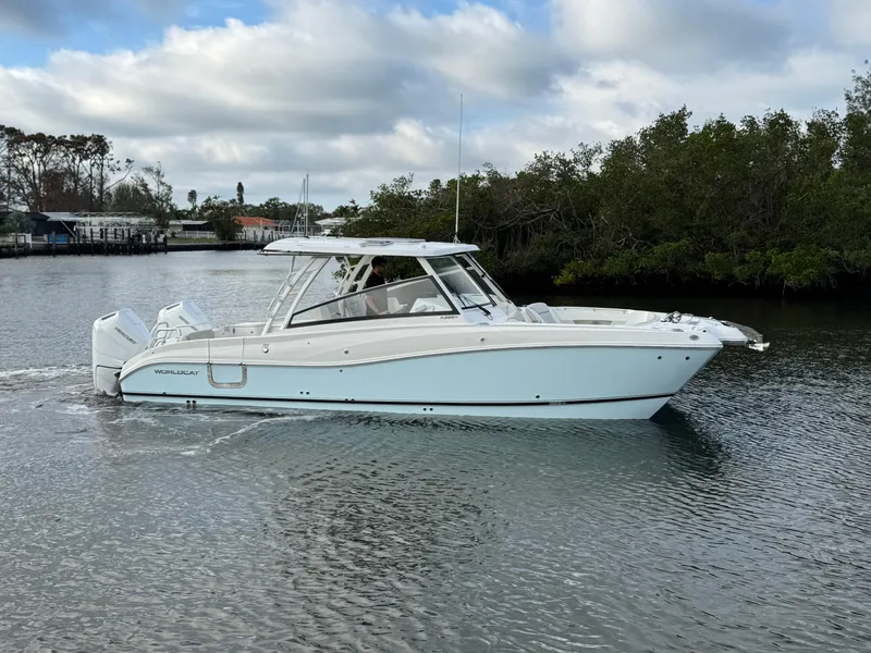 Slide: The Image of 2025 World Cat 325 DC boat cruising on a calm river. - 1