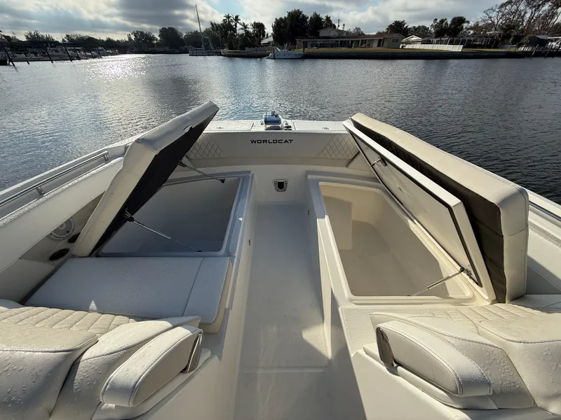 Slide: The Image of 2025 World Cat 325 DC boat with open storage compartments on a calm waterway. - 13