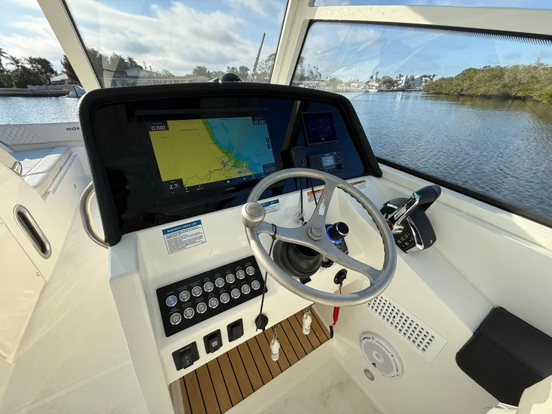 Slide: The Image of 2025 World Cat 325 DC boat dashboard with navigation system and steering wheel. - 20