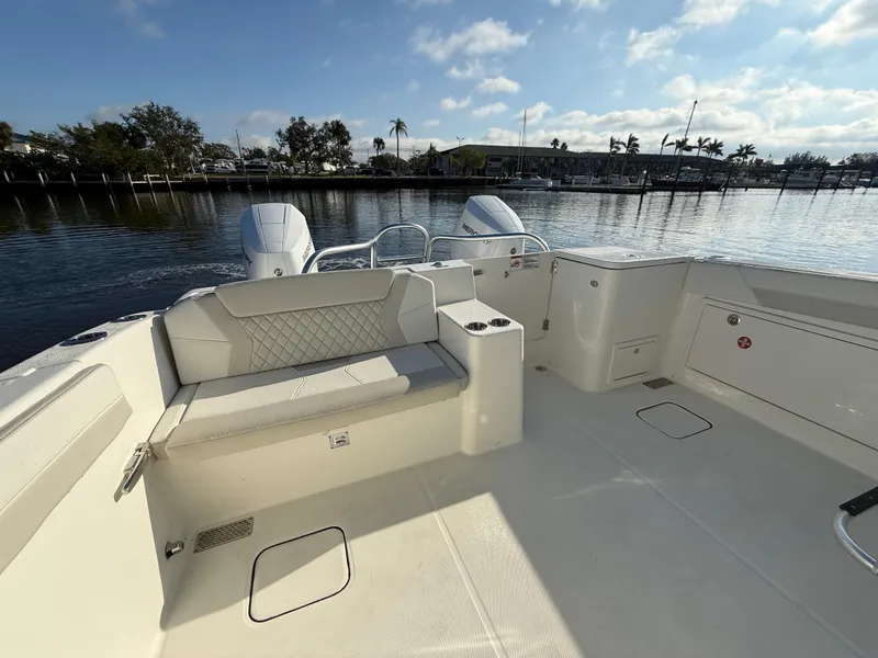 Slide: The Image of 2025 World Cat 325 DC boat interior with seating, docked by a scenic waterfront. - 24