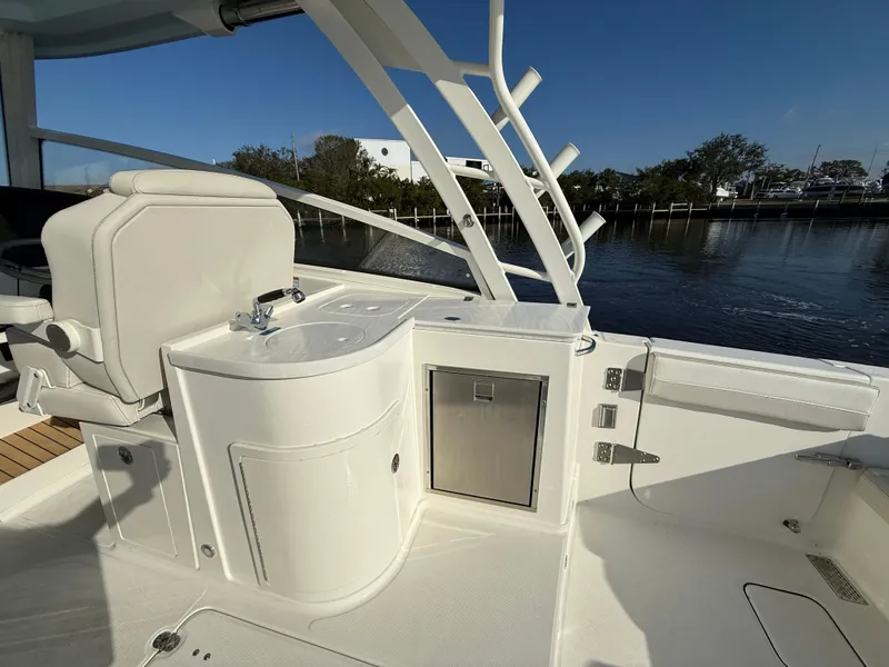 Slide: The Image of 2025 World Cat 325 DC boat interior with sink and storage, docked by calm waters. - 29