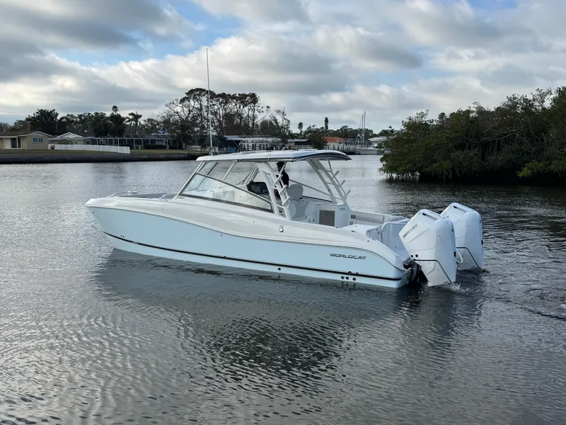 Slide: The Image of 2025 World Cat 325 DC boat on calm water, overcast sky. - 7