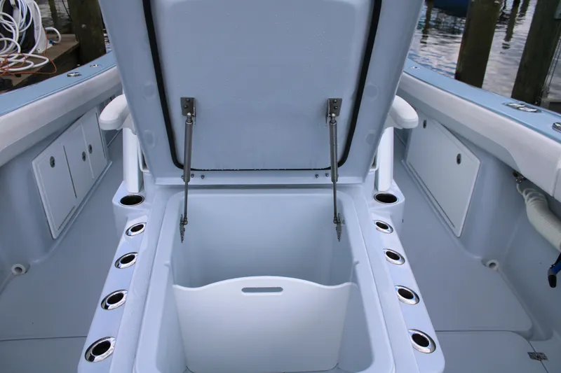Slide: The Image of 2024 Yellowfin 36 Offshore boat storage compartment with open lid and rod holders. - 11