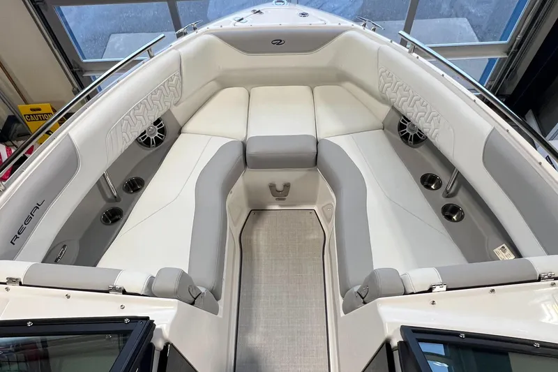 Slide: The Image of 2025 Regal LS4 boat interior with gray and white seating, cup holders, and speakers. - 19