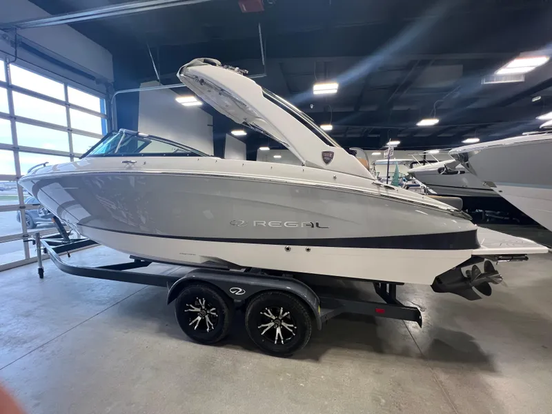 The Image of 2025 Regal LS4 boat in showroom, sleek design, on trailer. - 0