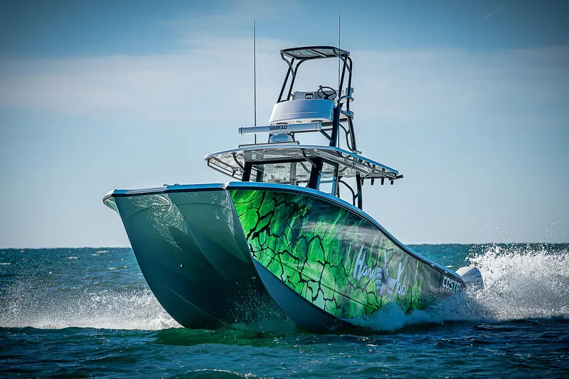 Slide: The Image of 2024 Costa Custom Boats 34 cruising on ocean with vibrant green hull design. - 0