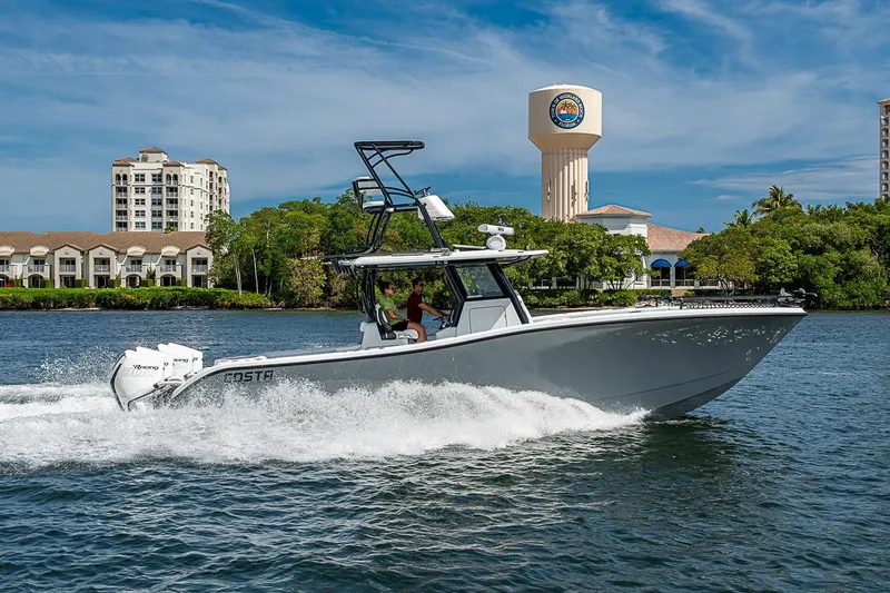 Slide: The Image of 2024 Costa Custom Boats 34 cruising on water near waterfront buildings and tower. - 106