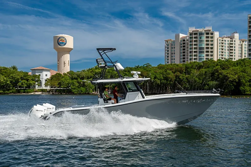 Slide: The Image of 2024 Costa Custom Boats 34 cruising on water near cityscape and greenery. - 108