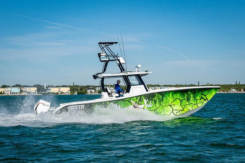 Slide: The Image of 2024 Costa Custom Boats 34 cruising on water with vibrant green design. - 22