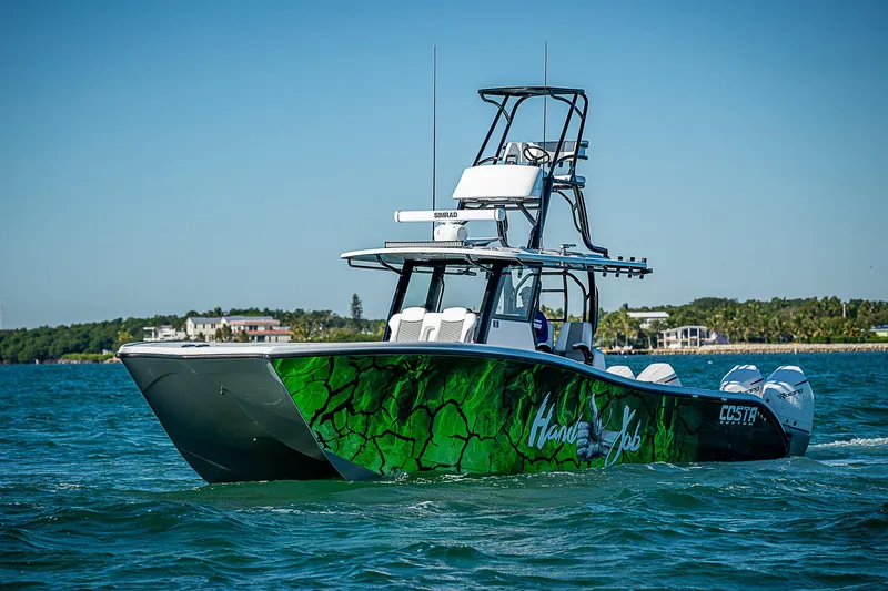 Slide: The Image of 2024 Costa Custom Boats 34 cruising on blue water with vibrant green hull design. - 37