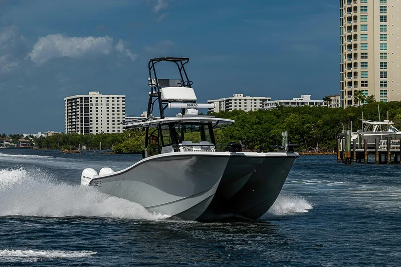 Slide: The Image of 2024 Costa Custom Boats 34 cruising in a coastal waterway with cityscape backdrop. - 117