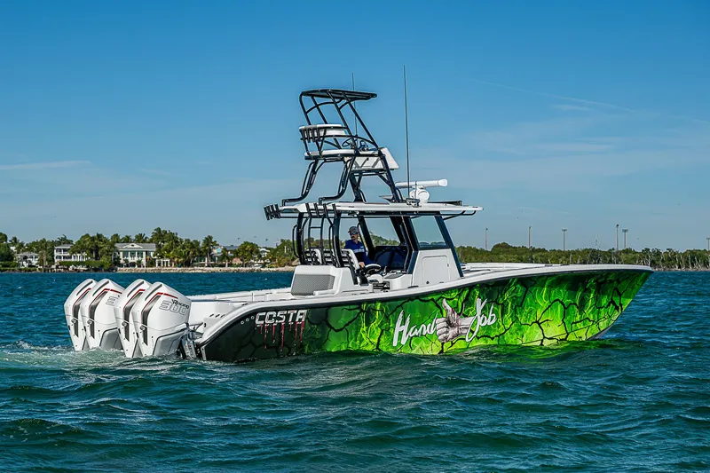 Slide: The Image of 2024 Costa Custom Boats 34 cruising on water with lush greenery in the background. - 48